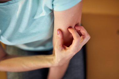 Kaşınan, kolları kaşınan, derisi kaşınan bir kadın..