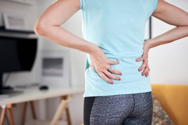 Sırtı ve kalçası ağrıyan bir kadın..