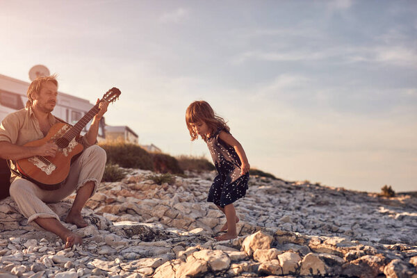 Отец с дочерью играют музыку, поют песни и наслаждаются летними вибрациями.