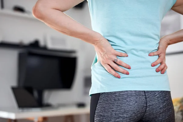 Woman with back and hip pain at home.