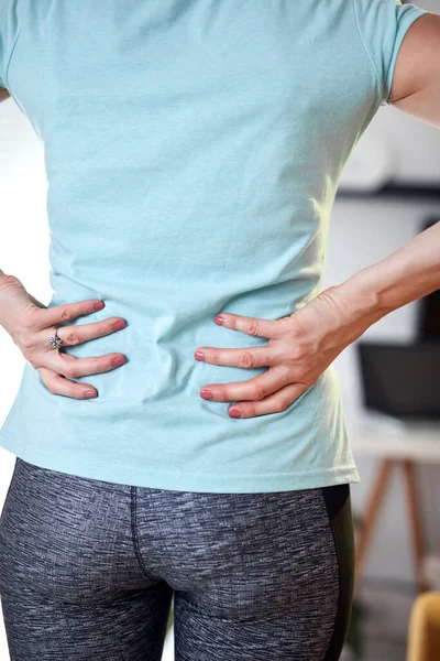 Woman with back and hip pain at home.