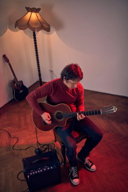 Erkek müzisyen retro vintage odasındaki amplifikatörde akustik gitar çalıyor..