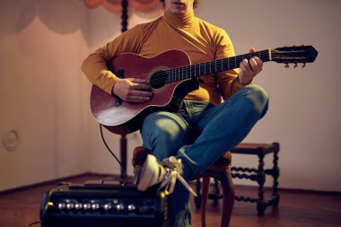 Erkek müzisyen retro vintage odasındaki amplifikatörde akustik gitar çalıyor..