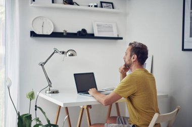 Yetişkin beyaz bir adam evde dizüstü bilgisayarla çalışıyor..