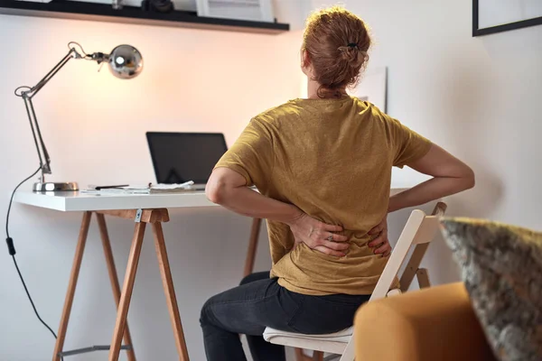 在家里的笔记本电脑上工作 背部和胃部疼痛的女人 — 图库照片