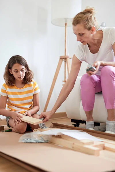 新しい家具を組み立てる母と娘 新しい家に移動 — ストック写真