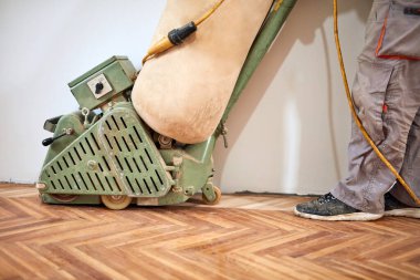 Tamirci zımpara makinesiyle parke onarıyor..