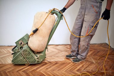 Tamirci zımpara makinesiyle parke onarıyor..