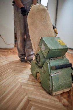 Tamirci zımpara makinesiyle parke onarıyor..