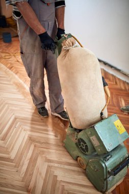 Tamirci zımpara makinesiyle parke onarıyor..