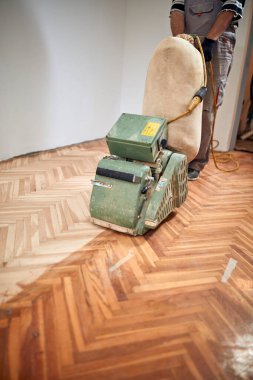 Tamirci zımpara makinesiyle parke onarıyor..