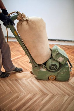 Tamirci zımpara makinesiyle parke onarıyor..