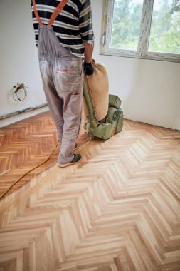 Tamirci zımpara makinesiyle parke onarıyor..