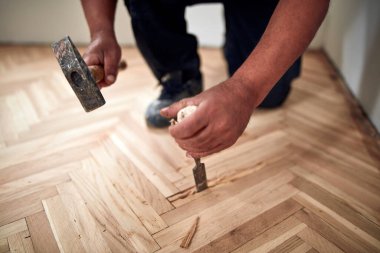 Tamirci zımpara makinesiyle parke onarıyor..