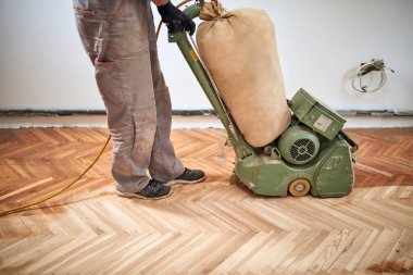 Tamirci zımpara makinesiyle parke onarıyor..