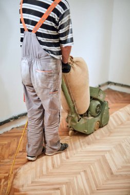 Tamirci zımpara makinesiyle parke onarıyor..