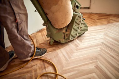 Tamirci zımpara makinesiyle parke onarıyor..