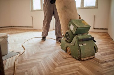 Tamirci zımpara makinesiyle parke onarıyor..