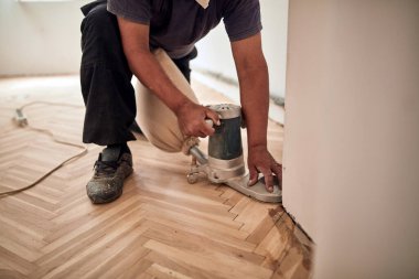 Tamirci zımpara makinesiyle parke onarıyor..