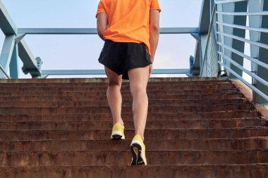 Sporcu sarı koşu ayakkabılarıyla merdivenleri çıkıyor..