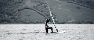 Rüzgar sörfçüsü nehirde rüzgarlı bir günde sörf yapıyor..