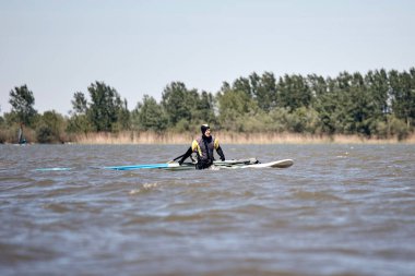 Rüzgârlı bir yaz gününde nehirde sörf yapan sörfçü..