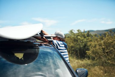 Rüzgâr sörfçüsü ve kampçı doğadaki bir arabadan bavulları hazırlayıp boşaltıyorlar..