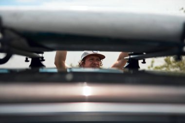 Rüzgâr sörfçüsü ve kampçı doğadaki bir arabadan bavulları hazırlayıp boşaltıyorlar..