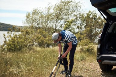 Rüzgâr sörfçüsü ve kampçı doğadaki bir arabadan bavulları hazırlayıp boşaltıyorlar..
