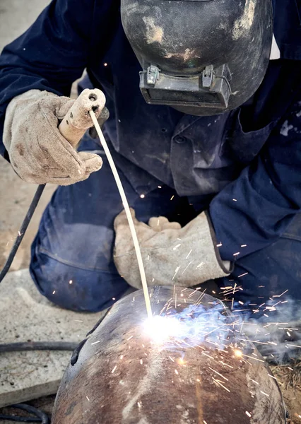 Construction worker arc welding the metal pipe.