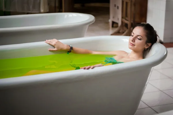 Женщина в ванной с зеленой водой — стоковое фото