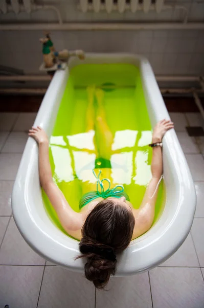 Donna in una vasca da bagno con acqua verde — Foto Stock