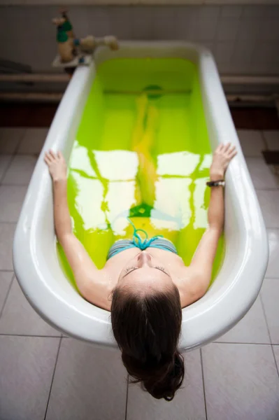 Женщина в ванной с зеленой водой — стоковое фото