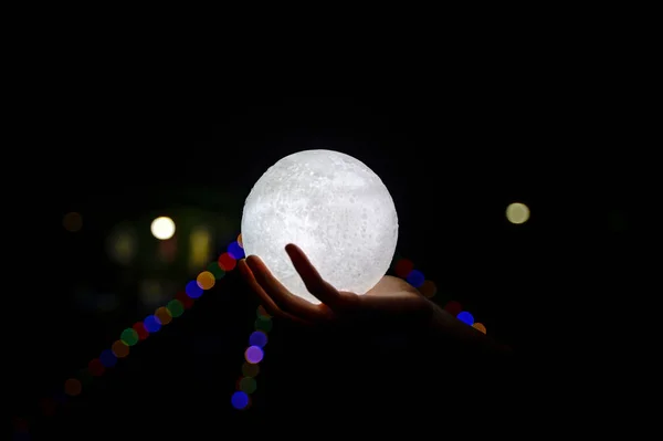 Изображение Руки Держащей Модель Луны Ночью Боке Стоковое Изображение