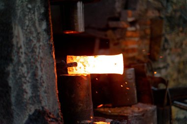 Demirci çeşitli aletler yapmak için çok sıcak demir dövüyor..