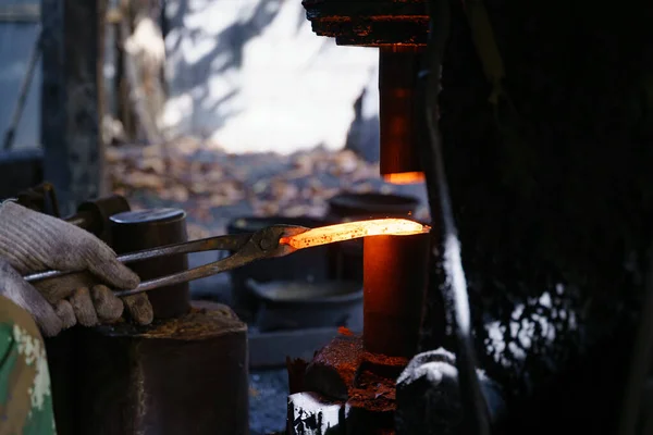 鍛冶屋は様々な道具を作るために非常に熱い鉄を鍛造しています — ストック写真