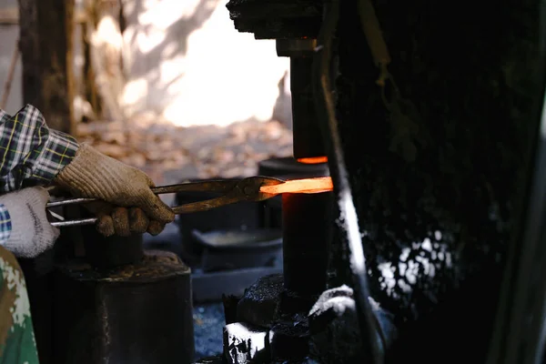 The blacksmith is forging very hot iron to make various tools.