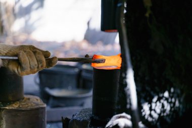 Demirci çeşitli aletler yapmak için çok sıcak demir dövüyor..