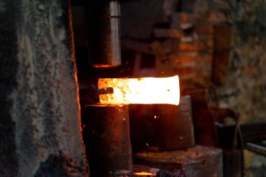 Demirci çeşitli aletler yapmak için çok sıcak demir dövüyor..