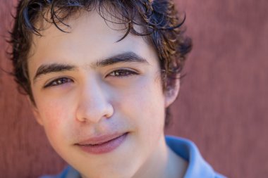 çocuk bir grunge kırmızı duvara yaslanmış gülümsüyor