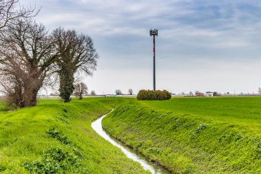 İtalya'da cep telefonu trellis yanındaki ekili alanlardan geçen sulama kanalı