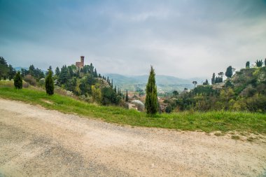 Ülke kir yol İtalya'da Brisighella köyünün saat kulesi yanında selvi ağaçları ile sınırlanmış