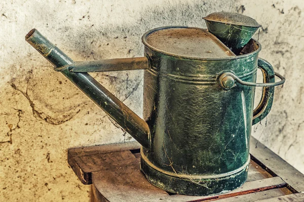 old metal green watering can covered with dust and cobwebs forgotten in a closet