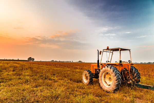 старый трактор и прицеп рядом с землей, где была собрана кукуруза
