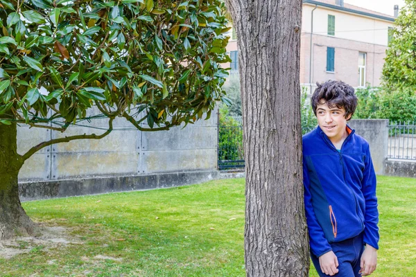 Молодий Хлопчик Посміхається Спираючись Стовбур Дерева Катальпи Саду — стокове фото