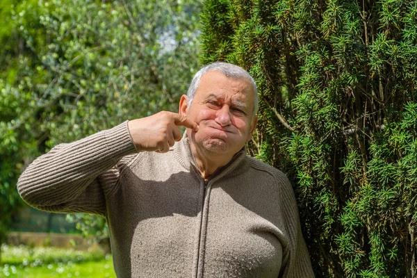 Idosos Caucasianos Jardim Verde Coloca Índice Bochecha Como Sinal Apreciação — Fotografia de Stock