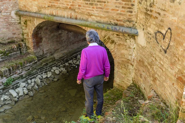 back of middle-aged man next to the walls of an ancient water channel spreading his arms