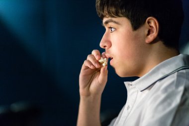 Çocuk sinemada film izlerken patlamış mısır yiyor