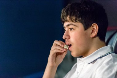 Çocuk sinemada film izlerken patlamış mısır yiyor