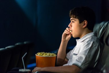 Çocuk sinemada film izlerken patlamış mısır yiyor